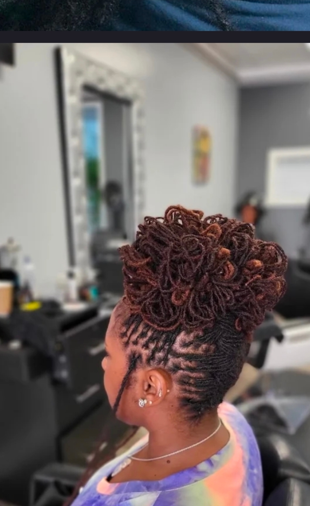 Woman with elegant loc bun updo clover earring black cape close-up side profile — loc updo specialist Delaware